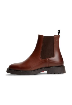 Botte Chelsea en cuir marron avec panneaux latéraux élastiques noirs, languette noire au talon et semelle épaisse en caoutchouc noir avec motif de la bande de roulement.