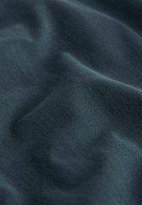 Tissu bleu foncé avec une texture fine et des plis doux créant des ombres et des reflets délicats.