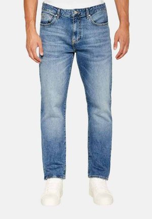 Jeans in denim azzurro chiaro con taglio dritto, design a cinque tasche e cuciture bianche, abbinati a sneaker bianche.