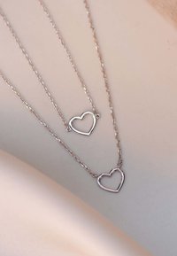 Zilveren hart pendant halskettingen in verschillende maten op delicate kettingen, met een gladde, glanzende afwerking en een open hartontwerp.
