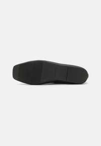 Suela de zapato negra con una superficie plana y texturizada, que presenta estrías y un área del dedo del pie suave. Las marcas incluyen "HECHO EN CHINA" y un número de talla.