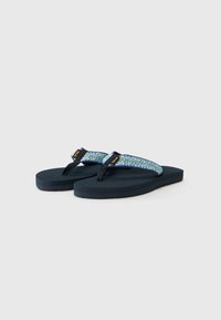 Blå mønstrede flip-flops med en mørkeblå gummisul og stofstropper, der har et geometrisk design. Accenter omfatter et logo mærke på stropen.