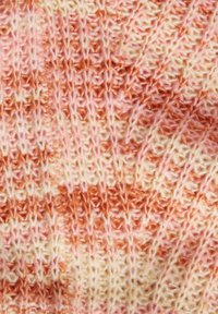 Pletená tkanina v pastelových odstínech růžové a krémové, s texturovaným vzorem s proplétanými prameny a jemnými barevnými variacemi.