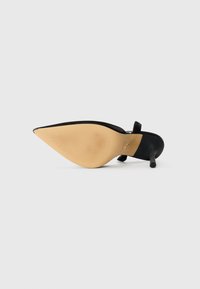 Musta korkokenkä, jossa on terävä kärki ja ohut korko, tekstiilinen kumipohja sekä ankle strap. Sileä päällinen, jossa on matta pinta.