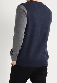 Męska bluza z kapturem w kolorze granatowym z szarymi rękawami, z prążkowanymi mankietami i pasem, wykonana z miękkiego materiału, o luźnym kroju.