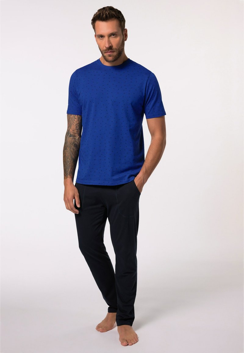 Camiseta azul de manga corta con un patrón texturizado y cuello redondo, combinada con pantalones de pijama negros con bolsillos.