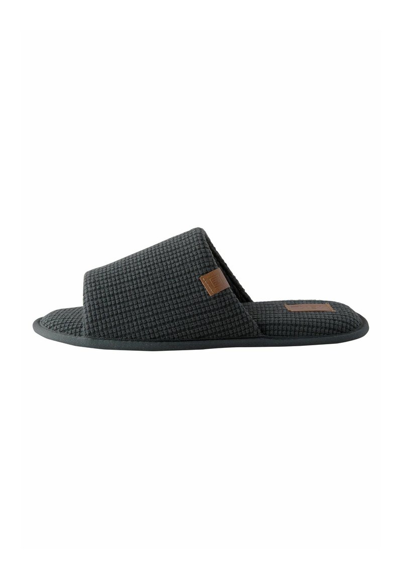 Chausson à glisser gris avec une texture en gaufre et un design bas, orné d'une accent en cuir tan sur le dessus. Semelle plate pour une utilisation en intérieur.