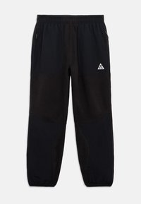 Melni flīsa sporta bikses ar elastīgu jostu, sānu kabatām un auduma paneļiem. Priekšpusē kreisajā pusē ir balta trīsstūra emblēma.