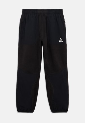 Μαύρες φλις φόρμες με ελαστική ζώνη, πλαϊνές τσέπες και πάνελ από ύφασμα. Περιλαμβάνουν λευκό τριγωνικό λογότυπο στην μπροστινή αριστερή πλευρά.