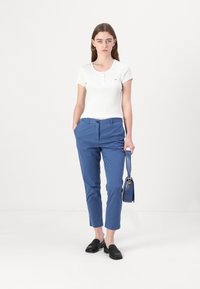 White short-sleeve ribbed shirt with buttons, blue tapered trousers, black slip-on shoes, and a blue crossbody bag. Simple design, solid colors.