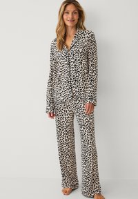 Leopardprint natdragtsæt lavet af blødt stof, der har lange ærmer, en notched krave og matchende brede bukser. Sorte detaljer langs kanterne.