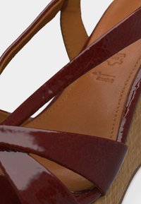 Κοντινή λήψη καφέ πέδιλου πλατφόρμας από λουστρίνι με δετές λωρίδες και υφασμένη σόλα.