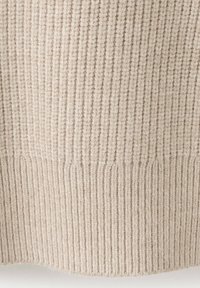 Gros plan d'un tissu tricoté beige côtelé avec des lignes texturées verticales et horizontales.