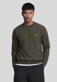 Sweatshirt verde oliva con collo a girocotolo a coste, maniche lunghe e un piccolo logo di un'aquila gialla sul petto. Tessuto di una consistenza liscia.