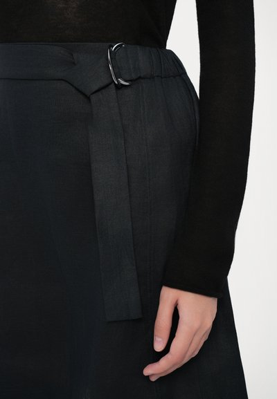 Lös passform, mörkgrå linnekjol med midjeband som har en svart metallring och en fastsatt tygdetalj i form av en knytning. Slät textur.