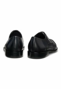 Scarpe in pelle nera con una texture liscia, caratterizzate da un tacco basso e una punta arrotondata. Presentano un branding discreto sul tallone e un design elegante.