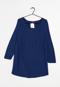 Granatowy, długi sweter z dzianiny z okrągłym dekoltem wiszący na czarnym wieszaku na białym tle.