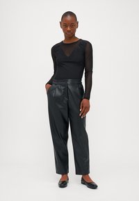 Haut noir à manches longues avec des manches transparentes et un col en V perlés, associé à un pantalon en cuir noir taille haute et des ballerines noires.