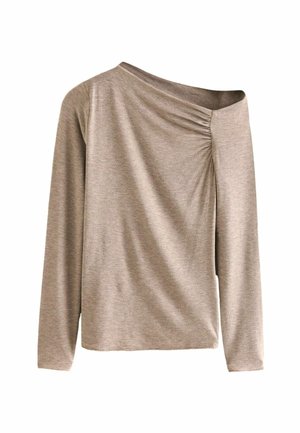 Haut asymétrique beige à manches longues avec une épaule légèrement dégagée et des fronces subtiles près de l'encolure sur fond blanc.