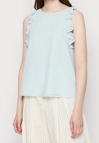 Top senza maniche di colore azzurro chiaro con dettagli arricciati sulle spalle, realizzato in un tessuto morbido e liscio con una vestibilità rilassata.