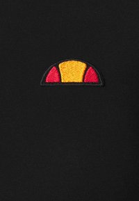 Black fabric with a small embroidered logo: a half-circle design featuring a yellow center and red sides on a black background.