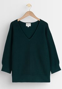 Suéter de punto verde oscuro con un profundo escote en V, hombros caídos, textura acanalada y dobladillo recto. Exhibido en un perchero de madera.