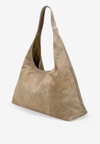 Bolso de hombro de ante beige con una abertura curva y amplia y una base plana. El interior cuenta con un forro más claro, lo que mejora la visibilidad.
