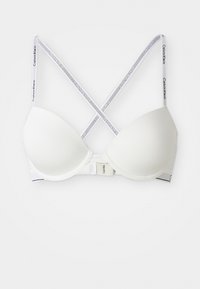 Witte gewatteerde beha met gekruiste Calvin Klein-merkbanden en haaksluiting op de rug, op een witte achtergrond.