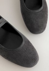 Grijze corduroy balletschoenen met een gladde zwarte binnenkant en elastische randen. Voorzien van een ronde neus en een gestructureerd ribbeloppervlak.