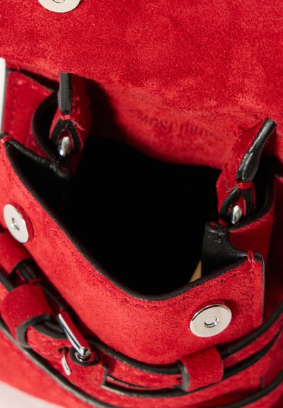 Κόκκινη σουέτ τσάντα χειρός με μαλακή υφή, με μαύρη επένδυση, ασημένια αξεσουάρ και ρυθμιζόμενους ιμάντες για κλείσιμο. Ορατή εσωτερική θέα.