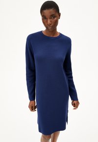Robe pull bleu marine à manches longues et col rond, avec un tricot texturé et des fentes sur les côtés pour faciliter le mouvement.