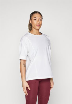 Valkoinen, lyhythihainen urheilu paita pyöreällä pääntiellä, jossa on tyylikäs, sileä pinta ja huomaamaton logotyyppinen yksityiskohta. Yhdistetty burgundin värisiin legginsseihin.