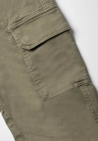 Khaki cargobroek van een gestructureerde stof, met een voorvak met klep, verstevigde naden en een ontspannen pasvorm.