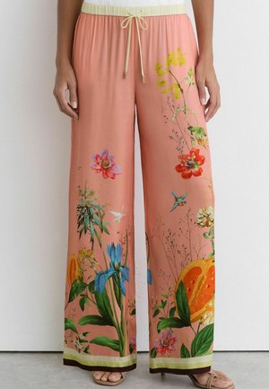 Pantalon corail à jambes larges avec taille à cordon, ornée d'imprimés colorés floraux, d'oiseaux et de fruits d'orange le long des jambes.