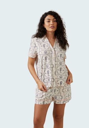 Short-sleeve, button-up pajama set in light pink with navy blue patterns featuring seashells and sea creatures. Soft fabric with a relaxed fit.
