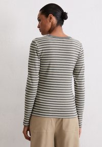 Koszula w paski z długim rękawem w kolorze szarym i kremowym, z okrągłym dekoltem i dopasowanym krojem. Gładka tkanina o jednolitej strukturze.