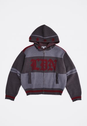 Szürke és sötétvörös kapucnis, elöl cipzáras kötött pulóver csillagmintákkal a kapucnin és "LDN" felirattal a mellrészen, bordázott mandzsettákkal és szegéllyel.