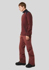 Maroon fleece pullover with a black collar, featuring a front pocket. Maroon cargo pants with multiple pockets and black accents. Black footwear.