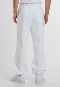 Witte sweatpants met elastische tailleband, taps toelopende benen en een enkele achterzak. Gemaakt van zachte stof met een gladde textuur.
