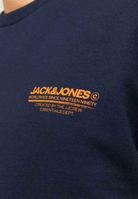 Camiseta de algodón azul marino con un logo naranja y texto en el pecho, diseño de cuello redondo y mangas cortas, con textura suave.
