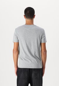 Tricou gri cu mânecă scurtă, realizat dintr-un material moale, având un guler în stil crew și o croială lejeră. Design simplu, fără modele sau accente.