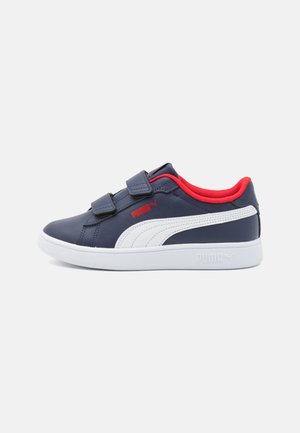 Tenis azul marinho com detalhes brancos, forro interior vermelho e duas tiras de Velcro. Material sintético liso, sola de borracha, logotipo na lateral.