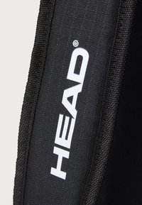 Tela negra con una superficie texturizada y bordes cosidos que muestra "HEAD" en grandes letras blancas, indicando la marca del producto.