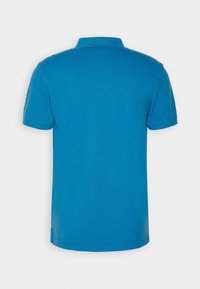 Camisa polo azul de manga corta mostrada desde atrás con un cuello acanalado y dobladillo recto sobre un fondo liso.