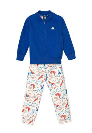 Blauw jack met ritssluiting en wit logo, gecombineerd met witte broek met rode en blauwe dinosaurussen en stripstijlpatronen.