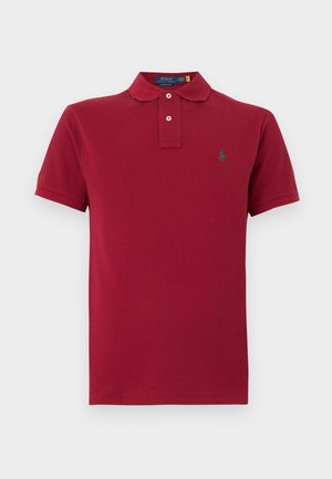 Polo rouge à manches courtes avec deux boutons blancs et un petit logo de cheval vert brodé sur le côté gauche de la poitrine.