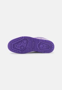 Semelle de chaussure de sport en caoutchouc violet avec un motif d'adhérence distinctif comprenant des éléments circulaires et linéaires ; logo bien visible au centre.