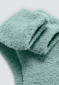 Toalla de baño turquesa, textura suave, plegada con fibras gruesas y suaves. Presenta un diseño limpio, sin patrones ni acentos visibles.