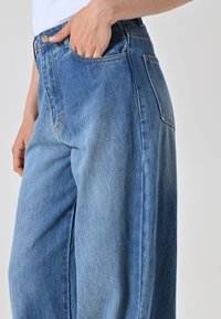 Lichtblauwe wijde jeans gemaakt van denim, met een hoge taille, een voorzak en subtiele stiksels langs de naden.
