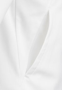 Tessuto bianco con una superficie liscia, dotato di un'apertura laterale per la tasca. Le cuciture sono ordinate, con bordi puliti e un design strutturato.